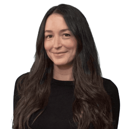 A woman with brown hair smiling at the camera, wearing a black top, in a quarter-length pose.