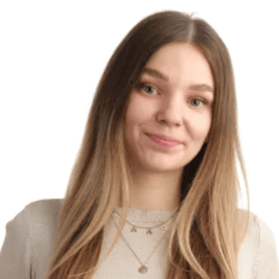 A woman standing against a white background with her head tilted slightly to the side.